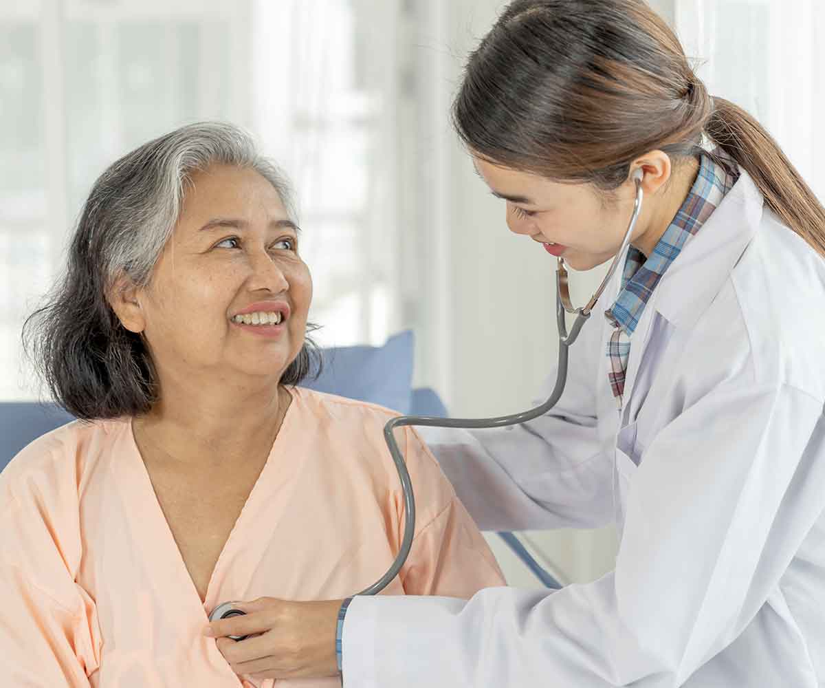A doctor listens to an elderly woman's heartbeat with a stethoscope.