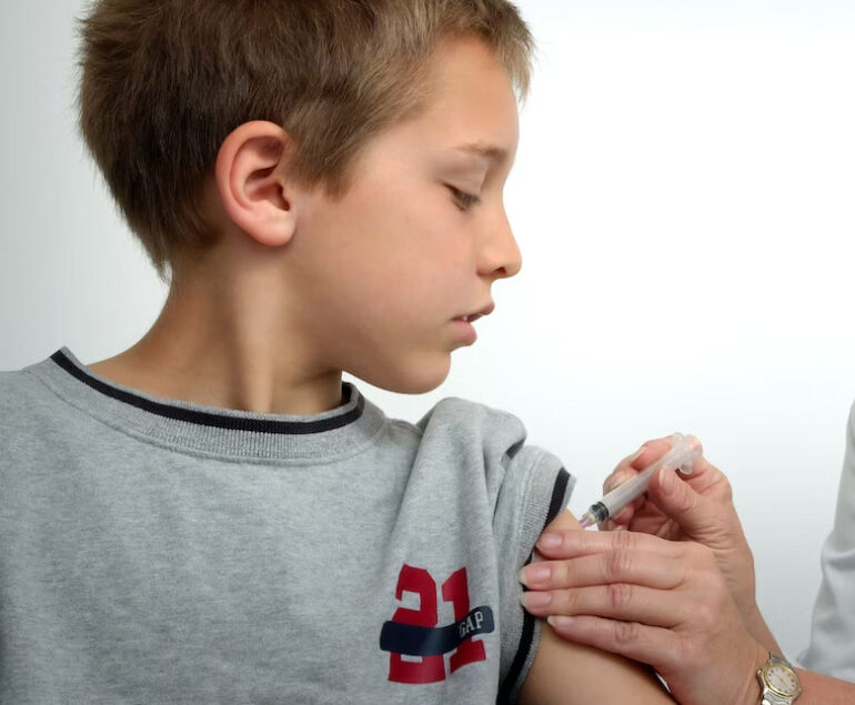 Young boy receiving a vaccine injection in his arm.
